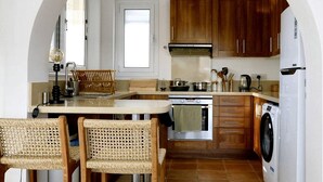 A kitchen with a central island, wooden chairs, a washing machine, and a stove. - Romantic High-End Pool 3-bedroom villa in Peyia, Cyprus (Peyia)