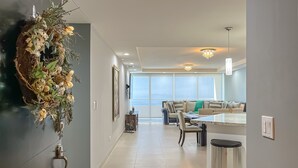 A modern kitchen with a central island, a dining area with a sofa, and a hallway with a decorative wall piece.