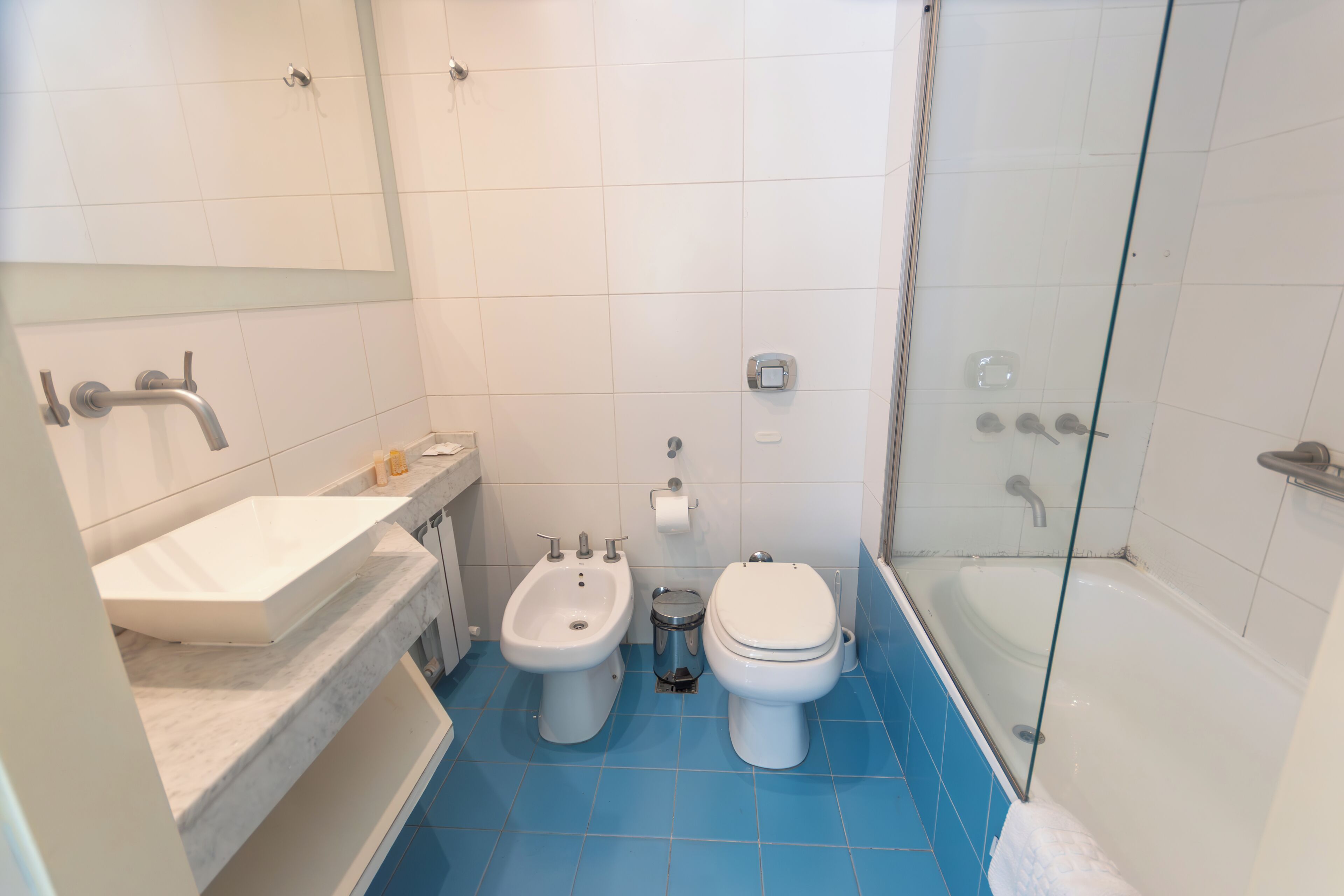 Une salle de bain équipée d’un bidet, de toilettes, d’un lavabo et d’une douche à parois en verre.