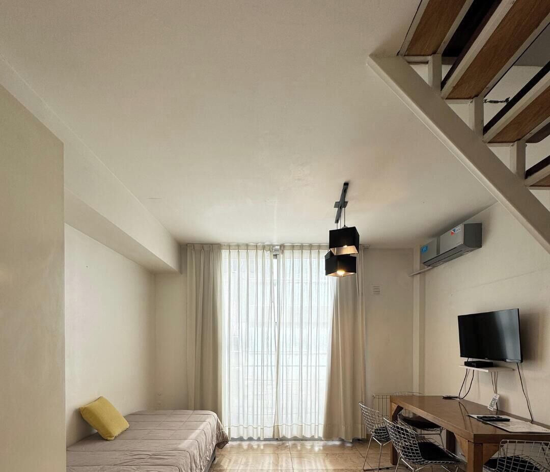Una moderna camera d'albergo con un letto, una scrivania con una sedia, una televisione e una finestra con tende.