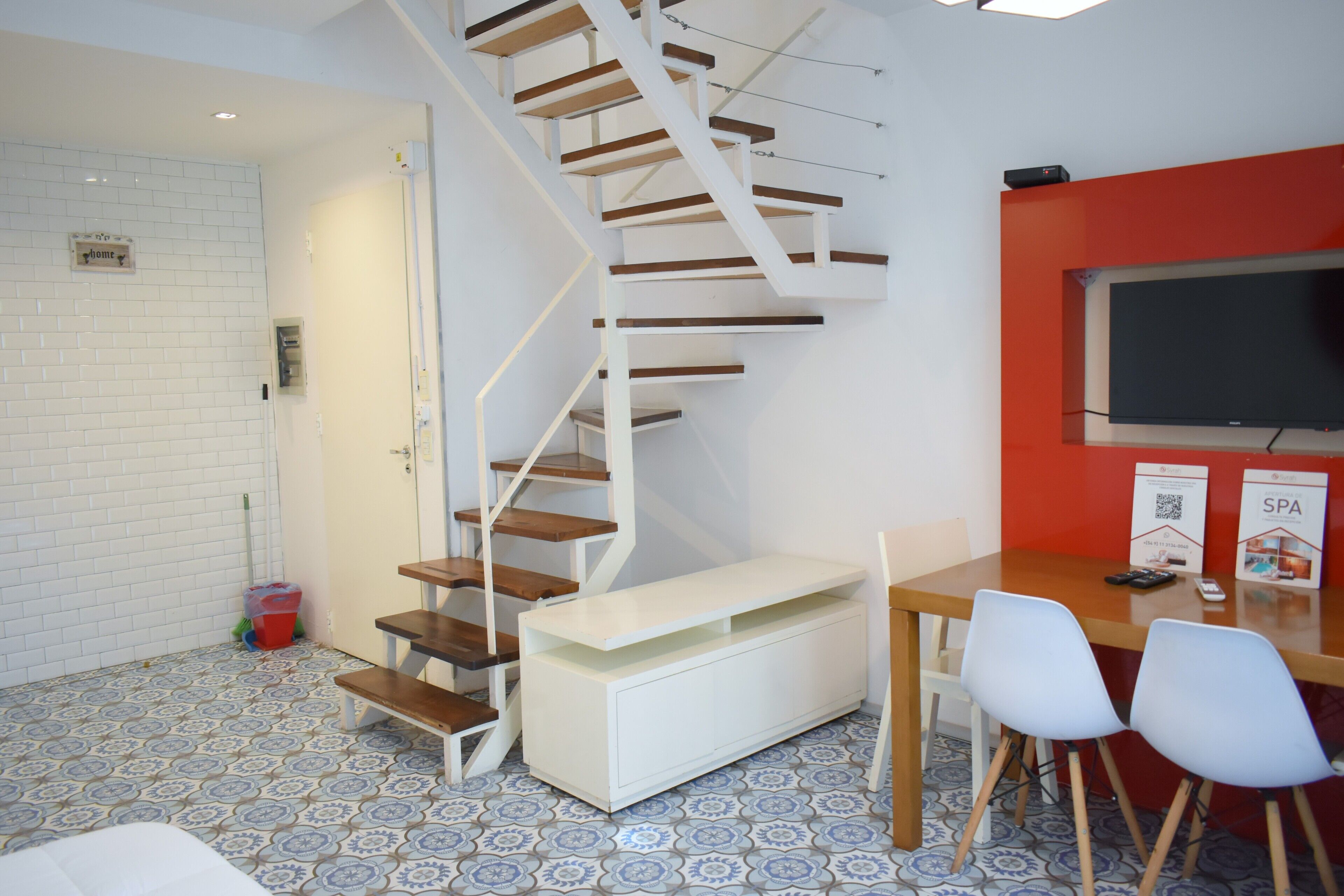 A modern interior with a spiral staircase, a dining area with chairs, a TV, and a spa sign.