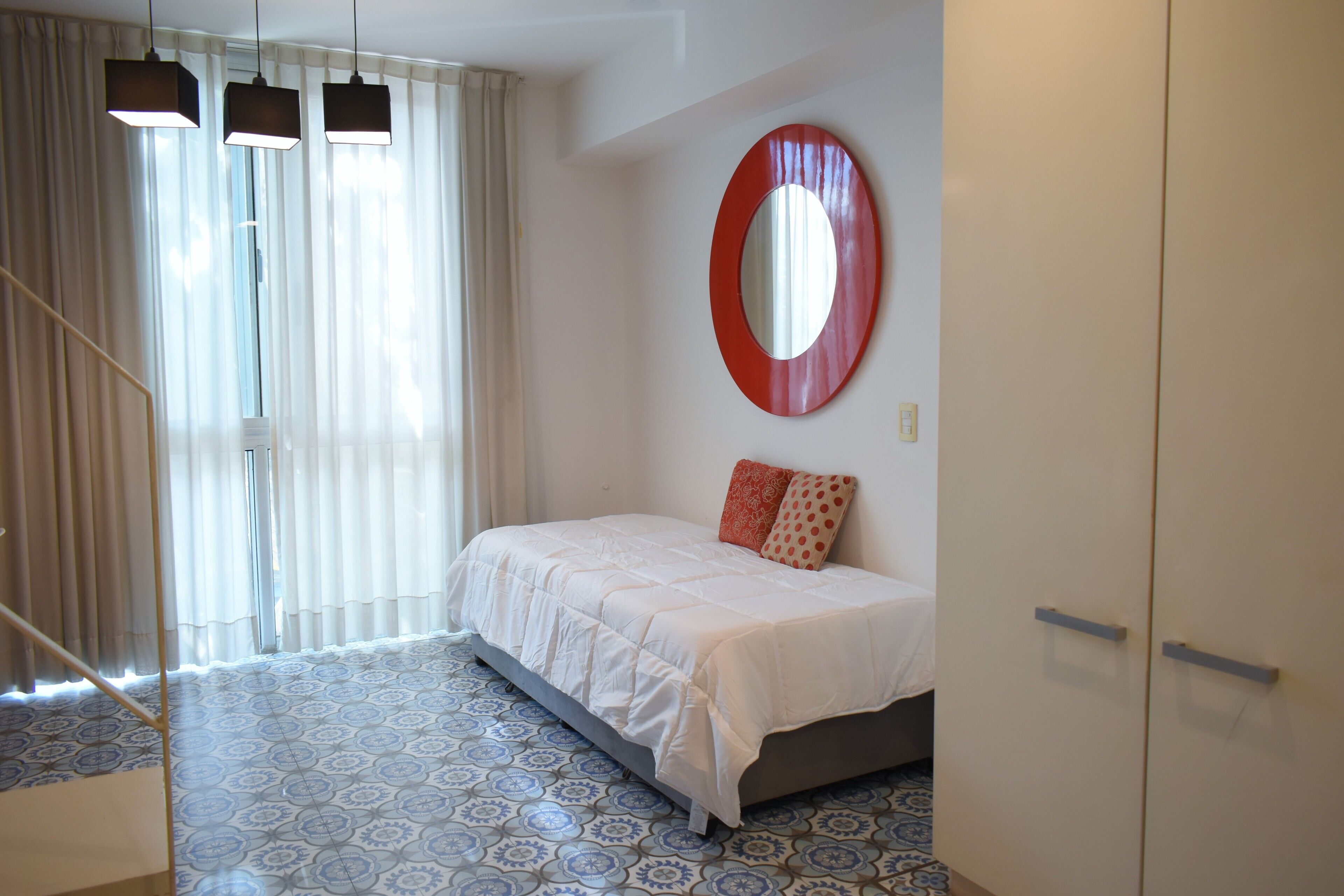 Un dormitorio con cama, un espejo grande y suelo estampado.