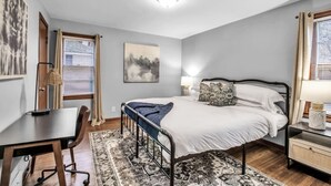 Un dormitorio con una cama individual, un escritorio, una silla, una lámpara y una ventana con persianas.