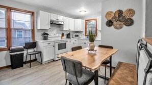 Una cocina moderna con armarios blancos, una mesa de comedor de madera y una planta en maceta.