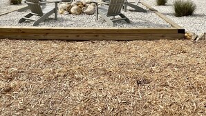 A two-story house with a covered patio area featuring Adirondack chairs and a fire pit. - Beautiful home on the river, mins to the Gulf; fire-pit, bar, view  (Steinhatchee)