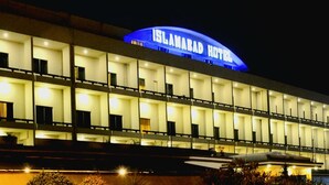 Un edificio de varios pisos con un cartel iluminado que dice 'ISLAMABAD HOTEL'.