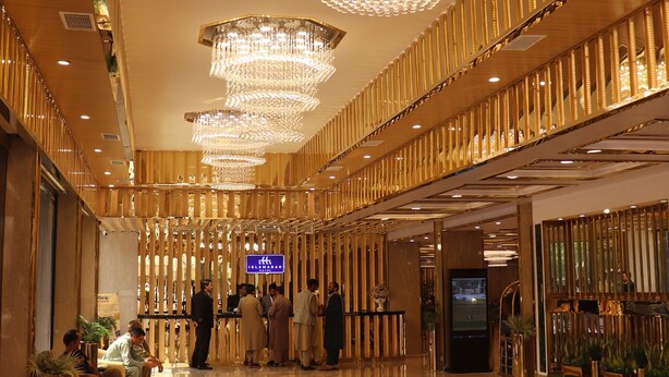 Un vestíbulo amplio con suelo de mármol pulido, grandes candelabros y un diseño moderno con paneles de madera verticales.