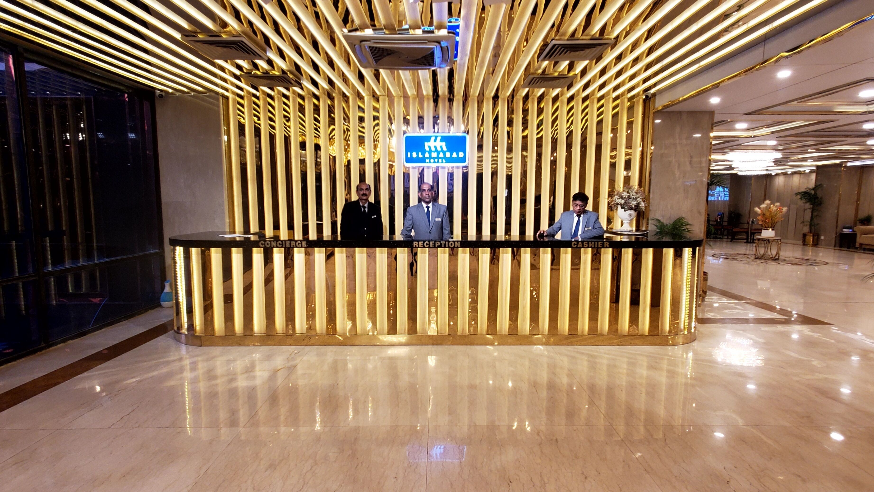 Un mostrador de recepción de hotel con diseño moderno, que incluye una zona de espera, conserjería y caja.