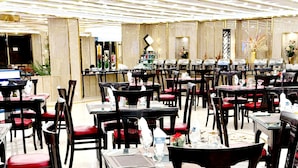 Un restaurante con varias mesas y sillas, algunas con cojines rojos.