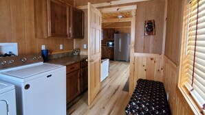 A compact kitchen with wooden cabinets, a washing machine, and a refrigerator.