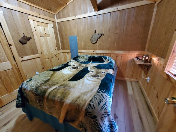 A wooden room with a bed, a door, and a wall-mounted shelf.
