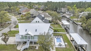 Una casa grande con un porche delantero, una piscina y un muelle que se extiende hacia un río.