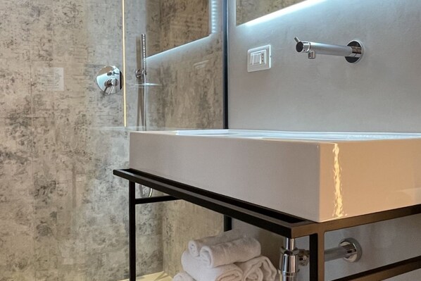 A bathroom with a large mirror, a sink, and a towel rack.