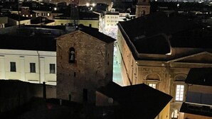 Een nachtzicht van een stadsbeeld met gebouwen, waaronder een opvallende toren en een gebouw met een balkon.