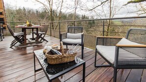 Una terraza de madera con mobiliario exterior, incluyendo una mesa y sillas, y una cesta de mimbre.