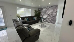 Una sala de estar moderna con un sofá de cuero oscuro, una mesa de centro y un amplio mural floral en la pared.