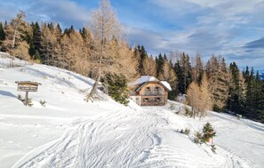 A wooden cabin with a sloped roof, surrounded by snow-covered ground and trees. - Ferienhuette in Lachtal (Lachtal - Schönberg)