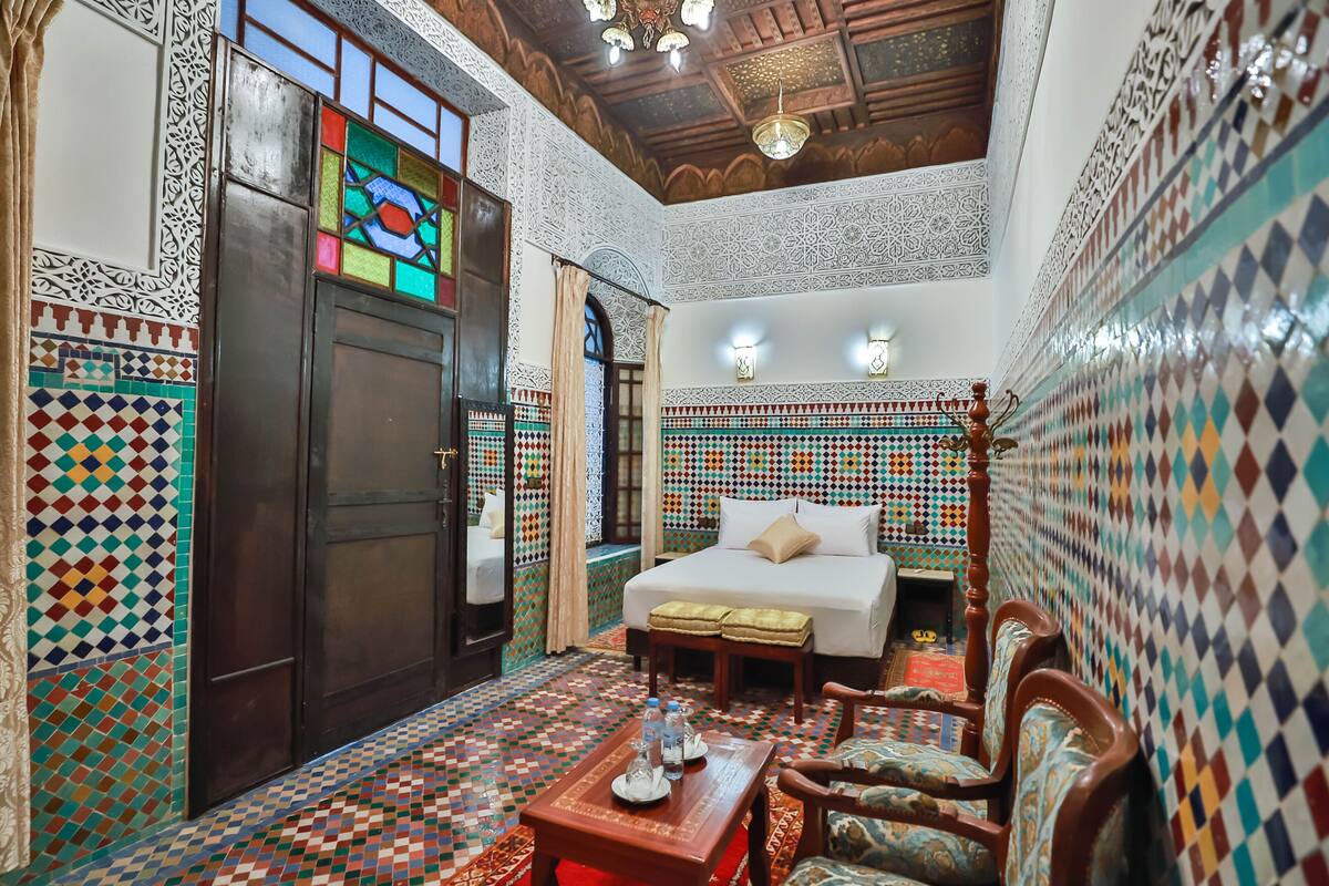 A room with a bed, wooden furniture, and a tiled floor.