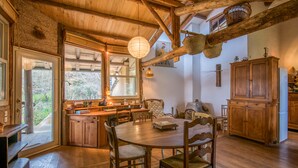 A rustic kitchen with wooden furniture, a dining table, and a large window overlooking a garden. - GiteleCun (Frayssinhes)