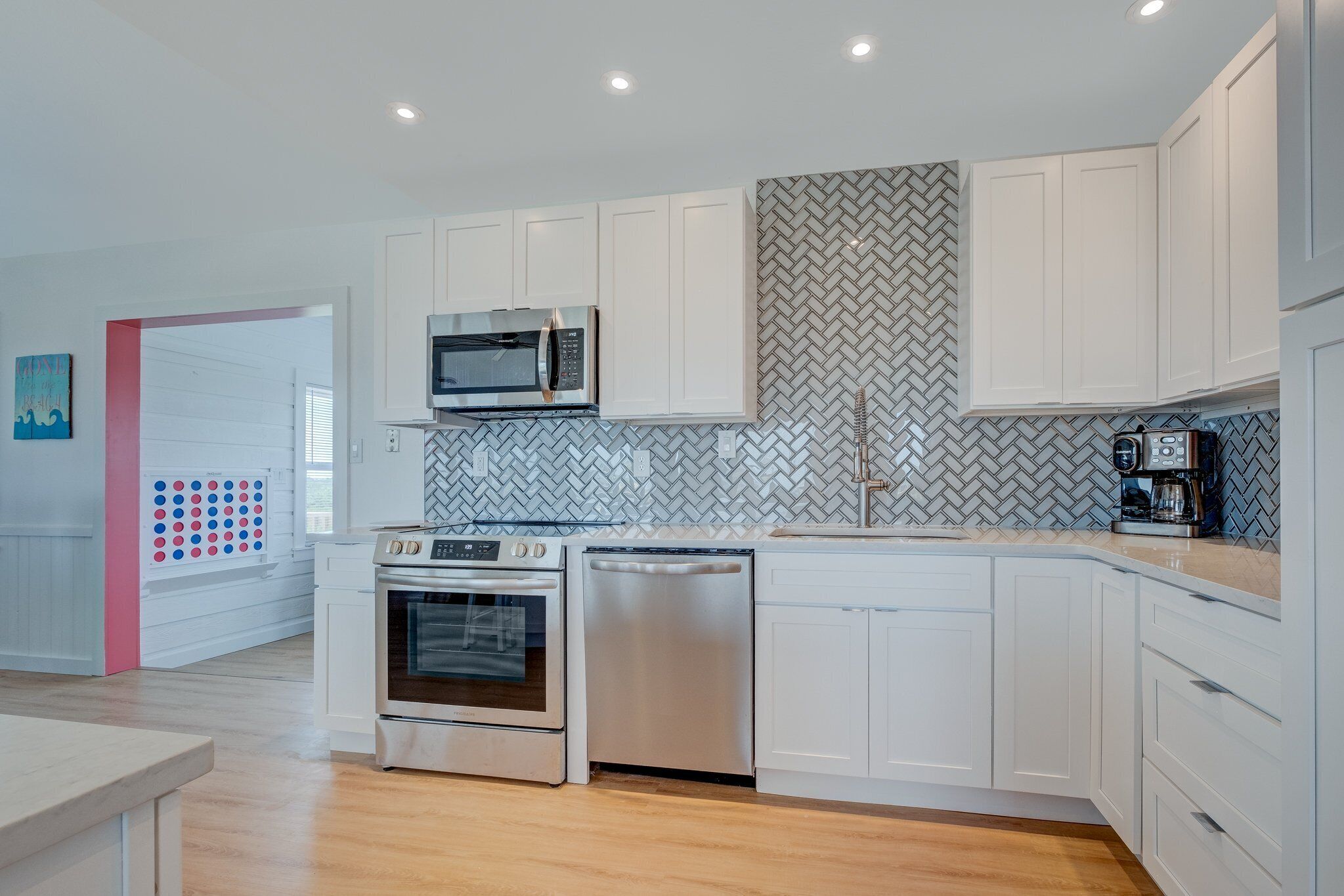 A modern kitchen with white cabinets, a microwave, oven, and dishwasher.