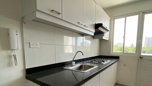 Una cocina moderna con armarios blancos, encimera negra y ventana que proporciona luz natural.