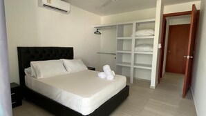 Un dormitorio ordenado con una cama, un armario y un equipo de aire acondicionado.