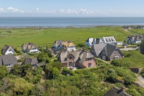 Un village côtier avec des maisons traditionnelles, un champ verdoyant et une vue sur la mer.