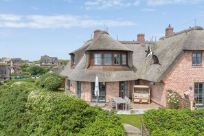 A traditional brick house with thatched roofs and a well-maintained garden.