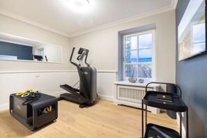 A home gym with a treadmill, a stationary bike, and exercise equipment stored in a suitcase. - Wattblick. Reet. Sauna. - Wattgeflüster (Sylt)