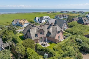 A coastal village with traditional thatched-roof houses, a paved driveway, and a clear view of the sea.