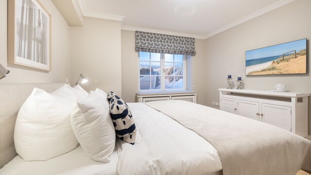 Une chambre à coucher avec un lit, une fenêtre donnant sur un beau paysage, une commode et un tableau accroché au mur.