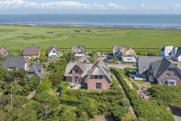 A coastal village with traditional houses, a clear view of the sea, and a well-maintained garden area.