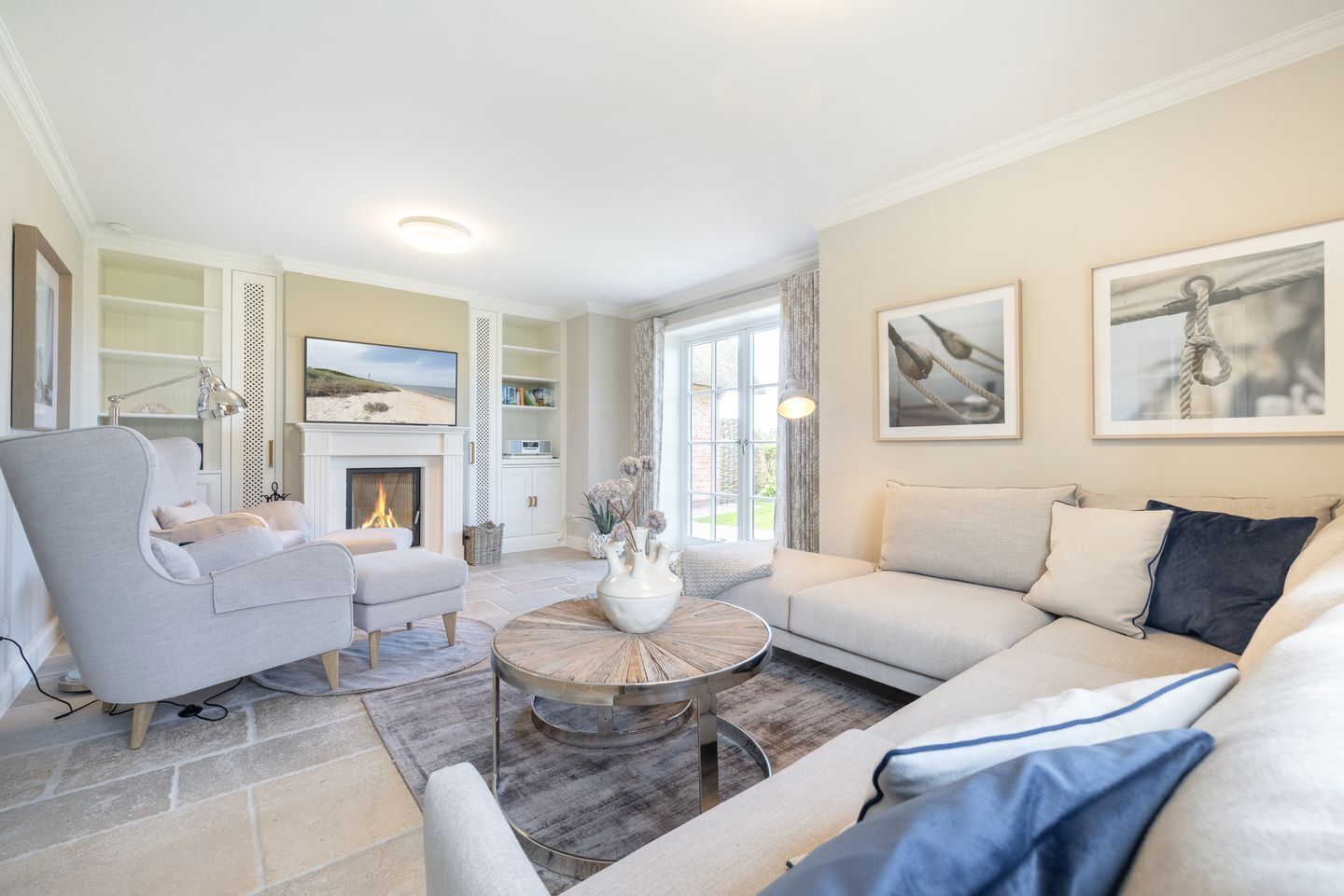 A spacious living room with a fireplace, a large sofa, a coffee table, and a bookshelf.