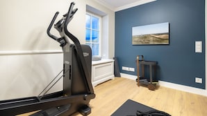 Une salle de sport à domicile équipée d’un vélo d’appartement, d’un tapis de course et d’un tapis de yoga, le tout installé sur un plancher en bois.