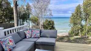 A gray sectional sofa with colorful pillows, a glass-top coffee table, and a view of the ocean.