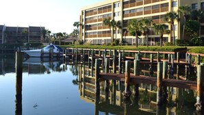 A waterfront hotel with a dock, reflecting the building and palm trees. - Beautiful Two Bedroom Condo at Midnight Cove II (Siesta Key)