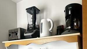Eine Küche mit Holzböden, auf denen Mixer, Kaffeemaschine und diverses Küchengeschirr stehen.