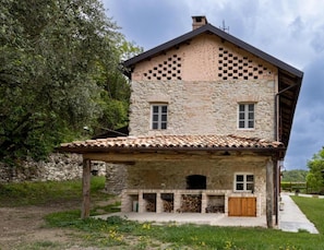Una casa de piedra con techo de tejas, un porche de madera y una pared de piedra.