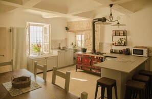 Una cocina con una isla central, estufa, microondas y una ventana con cortinas.