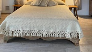 A bed with a wooden headboard, white bedding, and a decorative fringe. - Villa 'Casa Voglietti' with Private Pool, Wi-Fi and Air Conditioning (Murisengo)