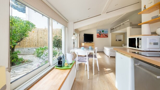 A modern kitchen with a dining area, a coffee machine, and a microwave. - Petite House-Studio with Terrace and Garden (cagnes sur mer)