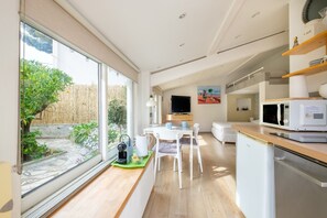 A modern kitchen with a dining area, a coffee machine, and a microwave. - Petite House-Studio with Terrace and Garden (cagnes sur mer)