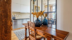 A dining area with a wooden table, chairs, and a vase with dried flowers. - Villa "Maison Avec Studio Cros De Cagnes" with Private Terrace, Wi-Fi, and Air Conditioning (cagnes-sur-mer)