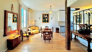 A dining area with a wooden table and chairs, a sofa, and a lamp. - Villa "Maison Avec Studio Cros De Cagnes" with Private Terrace, Wi-Fi, and Air Conditioning (cagnes-sur-mer)