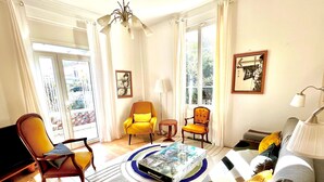 A well-lit living room with a sofa, armchairs, a coffee table, and a TV. - Villa "Maison Avec Studio Cros De Cagnes" with Private Terrace, Wi-Fi, and Air Conditioning (cagnes-sur-mer)