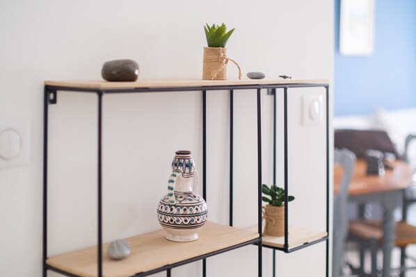 Uno scaffale con un vaso decorativo, una piccola pianta e una pietra.