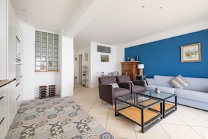 Una sala moderna con un sofá, sillones y una mesa de centro de vidrio.