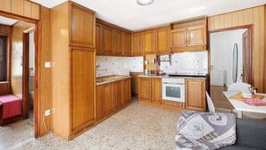 A compact kitchen with wooden cabinets, a white countertop, and a built-in oven. - Holiday Apartment 'Da Lule' with Mountain View, Balcony and Wi-Fi (Charvensod)
