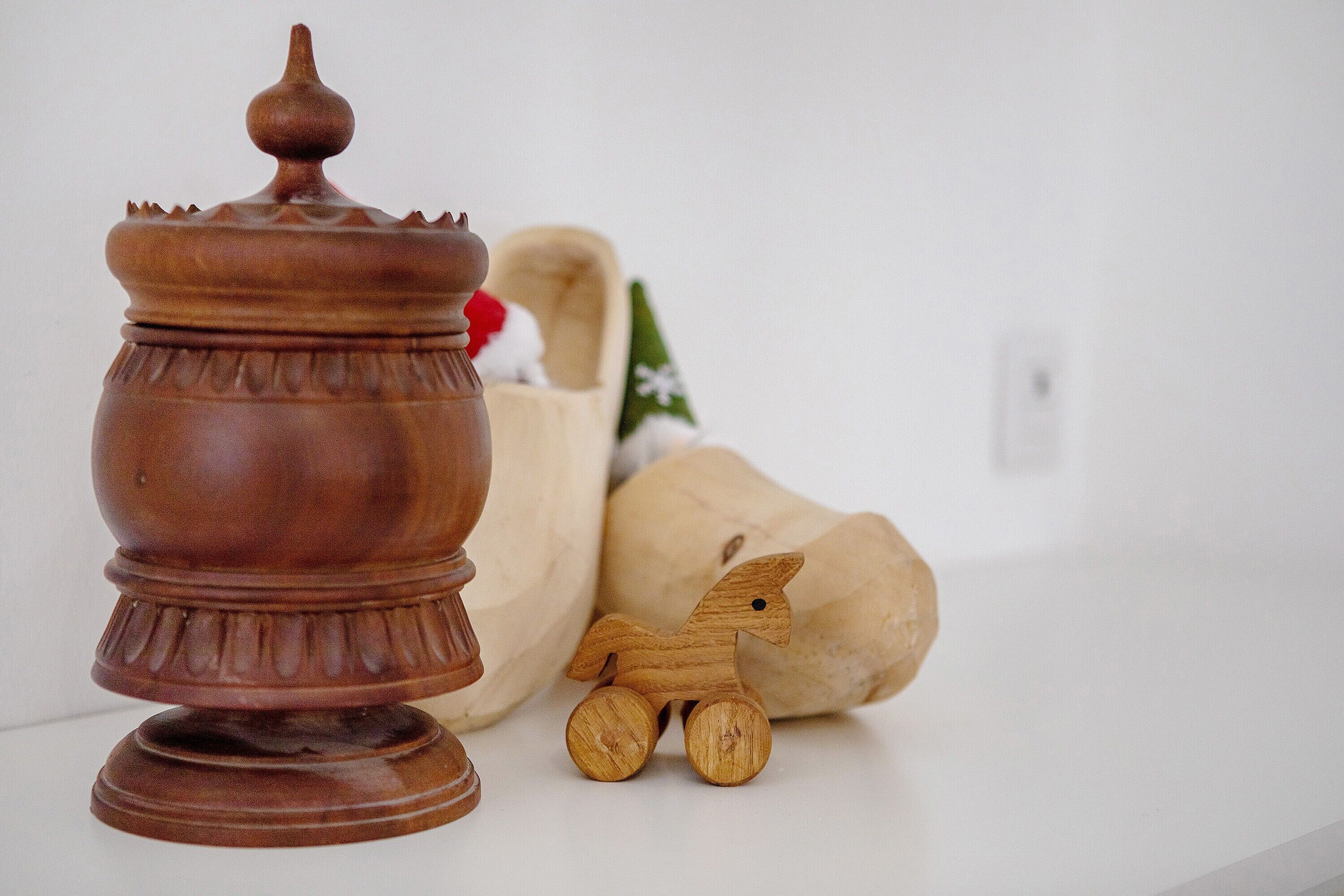 Un pot en bois avec un couvercle, une figurine de cheval en bois et un objet en bois ressemblant à une tête de cheval.