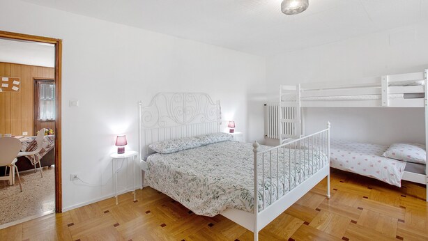 A bedroom with a bunk bed, a single bed, a bedside table with a lamp, and a mirror on the wall. - Holiday Apartment 'Da Lule' with Mountain View, Balcony and Wi-Fi (Charvensod)